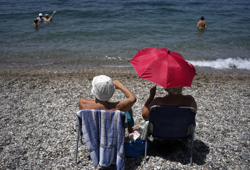 A woman uses an umbrella to protect herself from the sun at a beach in Loutraki, about 82 kilometres (51 miles) west of Athens, Greece, Thursday, July 20, 2023. Heat in Greece is expected to grow worse in the next five days, approaching 44 Celsius (111 Fahrenheit) and the country will face one more heatwave episode by the end of July, meteorologists warn. (AP Photo/Thanassis Stavrakis)