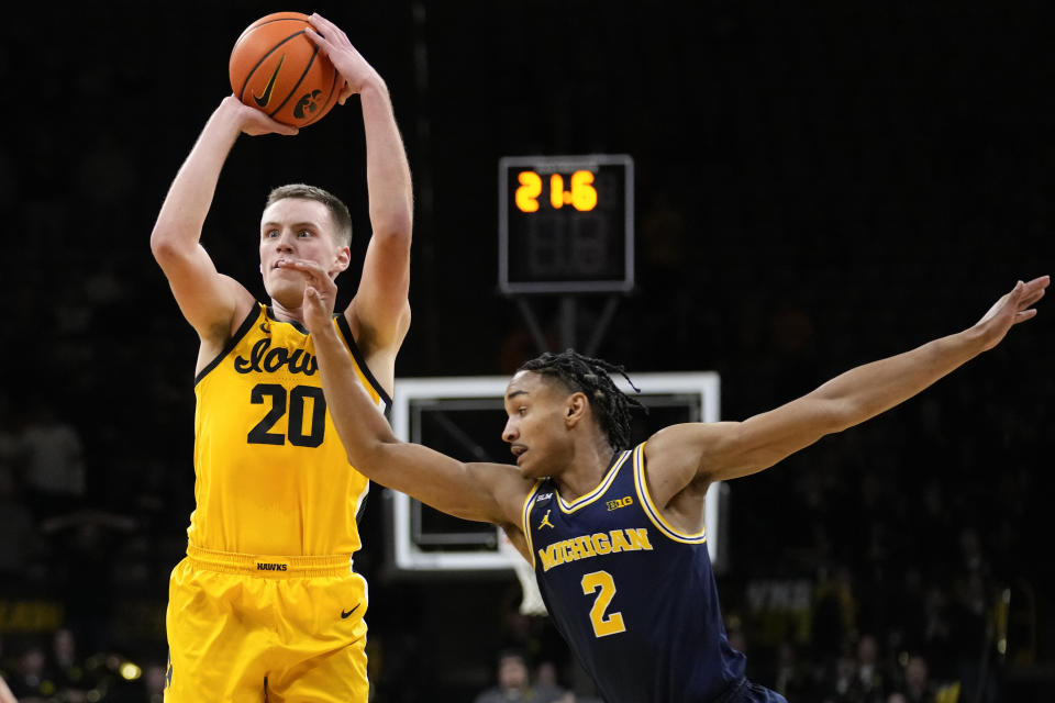 Iowa forward Payton Sandfort (20) is fouled by Michigan guard Kobe Bufkin (2) while shooting a 3-point basket during the second half of an NCAA college basketball game, Thursday, Jan. 12, 2023, in Iowa City, Iowa. Iowa won 93-84 in overtime. (AP Photo/Charlie Neibergall)