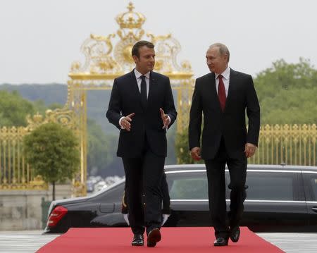 Russian President Vladimir Putin (R) and French President Emmanuel Macron walk during a meeting at the Chateau de Versailles near Paris, France, May 29, 2017. Sputnik/Mikhail Metzel/Kremlin via REUTERS