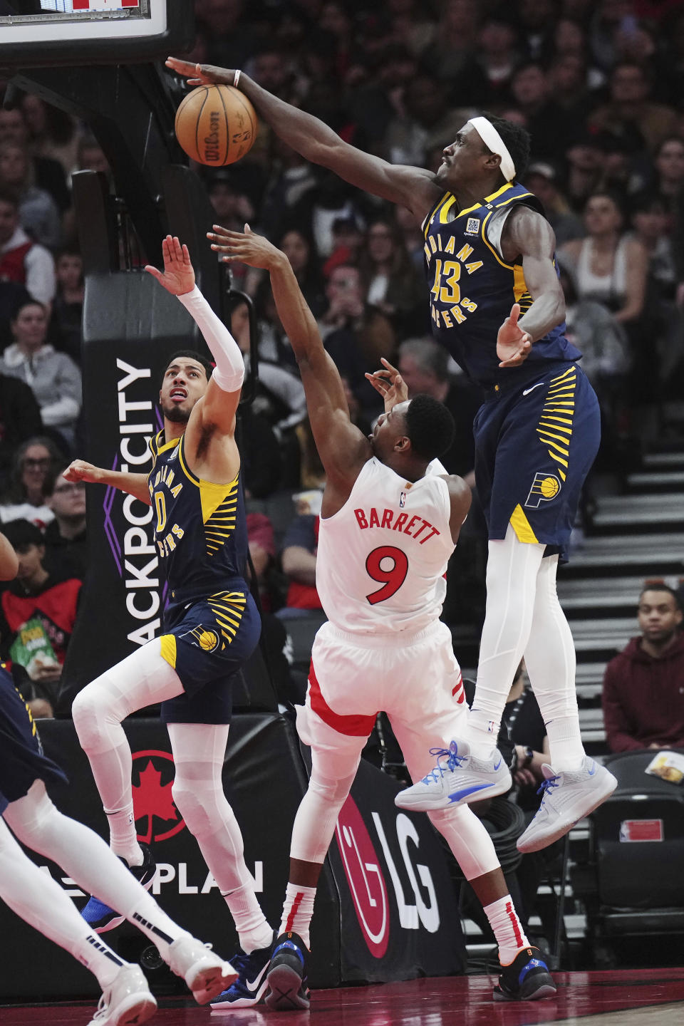 Indiana Pacers forward Pascal Siakam (43) blocks a shot by Toronto Raptors guard RJ Barrett (9) as Pacers guard Tyrese Haliburton (0) defends during the first half of an NBA basketball game in Toronto on Tuesday, April 9, 2024. (Nathan Denette/The Canadian Press via AP)
