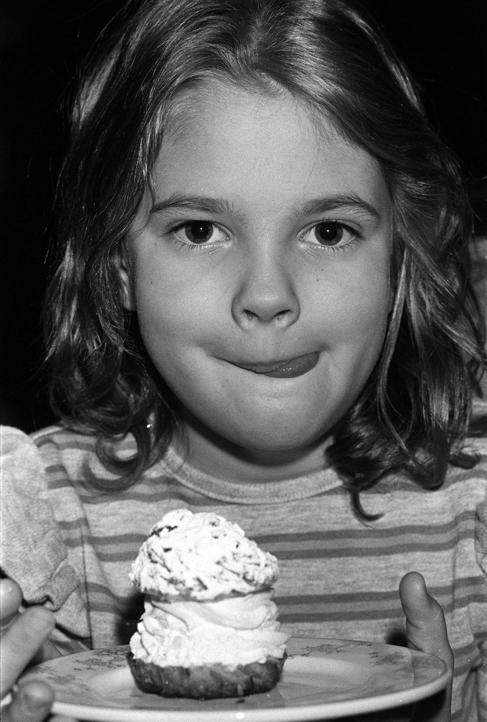 Seven year old American actress Drew Barrymore, star of the movie ET, about to eat an English teacake at the Inn on the Park, in London. Drew is the grand-daughter of silent movie star John Barrymore.   (Photo by PA Images via Getty Images)