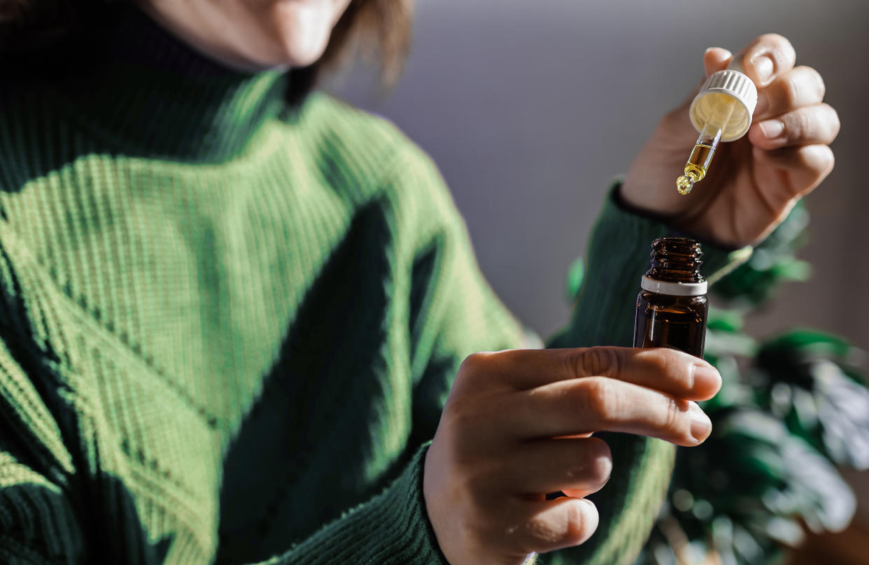 Woman holding a dropper of sublingual cbd 