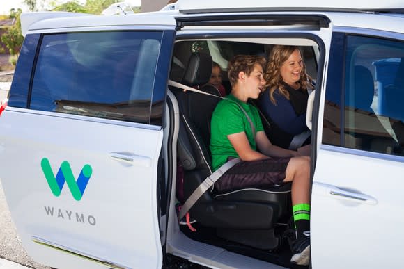 Woman and kids in minivan with Waymo logo on the side.