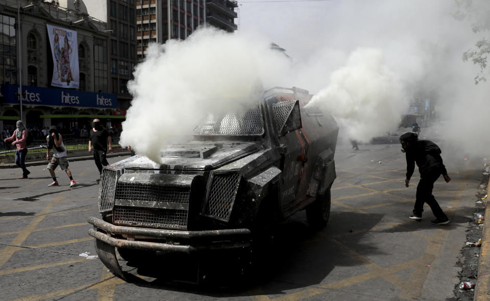 A police armored vehicle spews tear gas during clashed in Santiago, Chile, Wednesday, Oct. 23, 2019. Rioting, arson attacks and violent clashes wracked Chile as the government raised the death toll to 15 in an upheaval that has almost paralyzed the South American country long seen as the region's oasis of stability. (AP Photo/Rodrigo Abd)