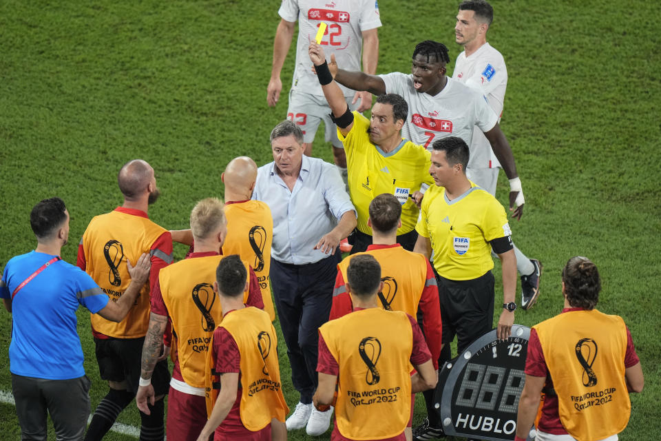 Referee Fernando Rapallini displays a yellow card to a Serbian player from the bench during the World Cup group G soccer match between Serbia and Switzerland, at the Stadium 974 in Doha, Qatar, Friday, Dec. 2, 2022. (AP Photo/Luca Bruno)