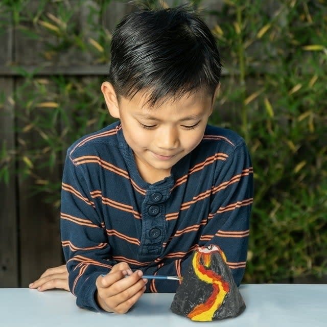 child painting a mini volcano