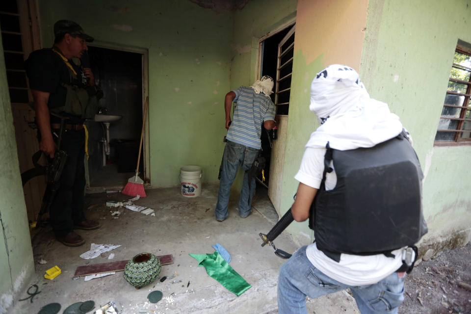 Vigilantes or members of the community police enter a house after coming to the village of Paracuaro and taking over control, in Michoacan state