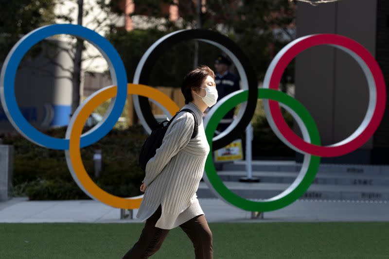 A woman wearing a protective face mask, following an outbreak of the coronavirus disease (COVID-19), walks past the Olympic rings in front of the Japan Olympics Museum in Tokyo