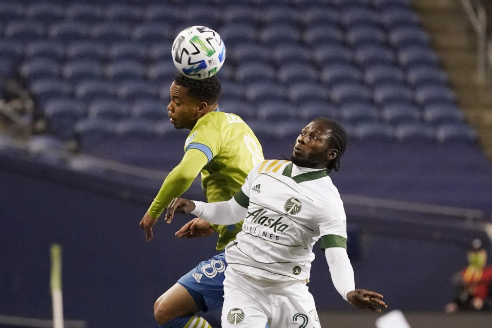 Seattle Sounders' Jordy Delem (8) heads the ball in front of Portland Timbers' Yimmi Chara in the first half of an MLS soccer match, Thursday, Oct. 22, 2020, in Seattle. (AP Photo/Elaine Thompson)