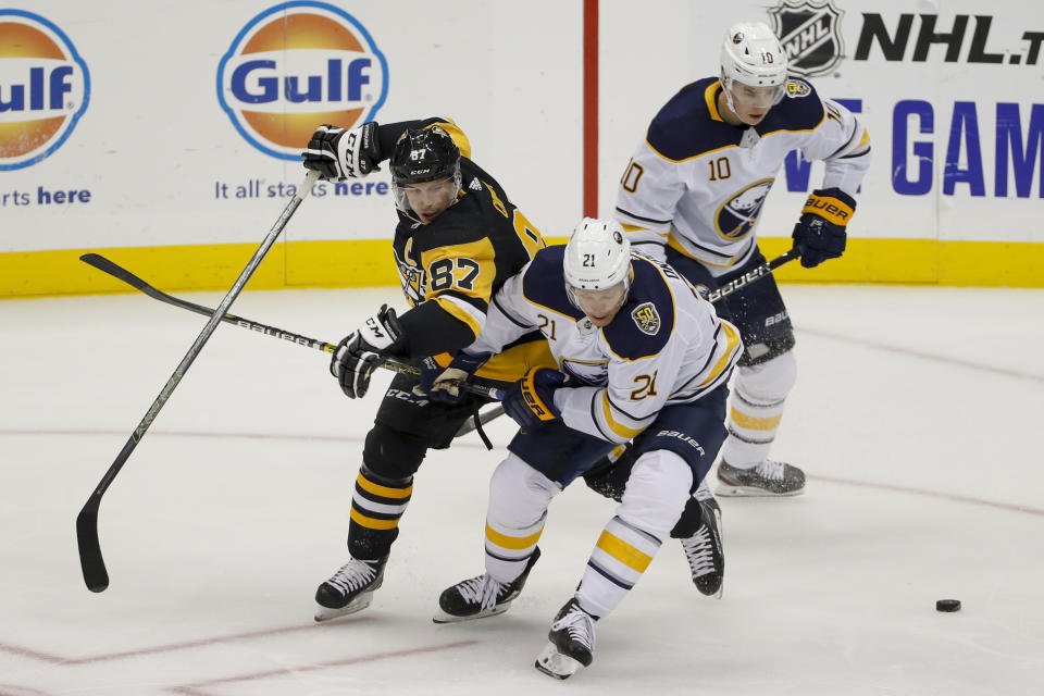 Pittsburgh Penguins' Sidney Crosby (87) and Buffalo Sabres' Kyle Okposo (21) tangle as they try to control the puck in front of Henri Jokiharju (10) during the first period of an NHL preseason hockey game, Saturday, Sept. 28, 2019, in Pittsburgh. (AP Photo/Keith Srakocic)