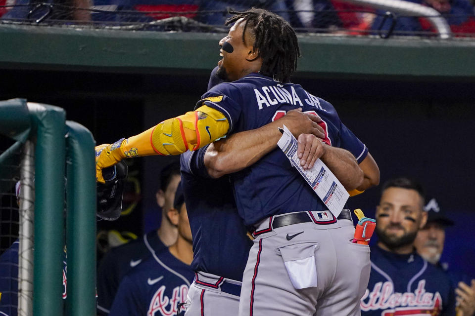 Atlanta Braves' Ronald Acuña Jr. gets a hug from Atlanta Braves manager Brian Snitker in the dugout after hitting a solo home run during the first inning of a baseball game against the Washington Nationals at Nationals Park, Friday, Sept. 22, 2023, in Washington. With the hit, Acuña became the fifth player in MLB history with 40 home runs and 40 stolen bases in a season. (AP Photo/Andrew Harnik)