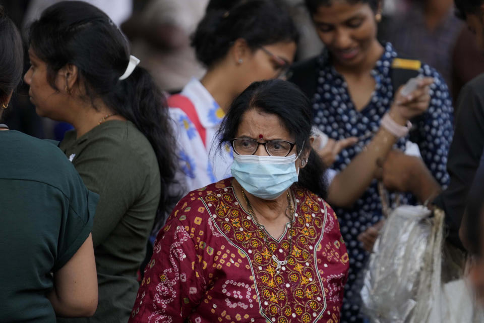 A woman wearing a face mask walks through a busy shopping district in Mumbai, India, Thursday, Dec. 22, 2022. India has begun randomly testing international passengers arriving at its airports for COVID-19, the country’s health minister said Thursday, citing an increase in cases in neighboring China and also asked the public to wear masks and maintain social distancing. (AP Photo/Rafiq Maqbool)