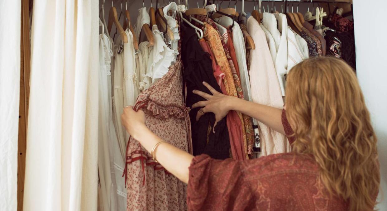 A woman looks through her wardrobe [Photo: Getty]