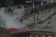 Protesters run away as police officers use teargas to disperse people demonstrating against police brutality in Lagos, Nigeria, Wednesday Oct. 21, 2020. After 13 days of protests against alleged police brutality, authorities have imposed a 24-hour curfew in Lagos, Nigeria's largest city, as moves are made to stop growing violence. ( AP Photo/Sunday Alamba)