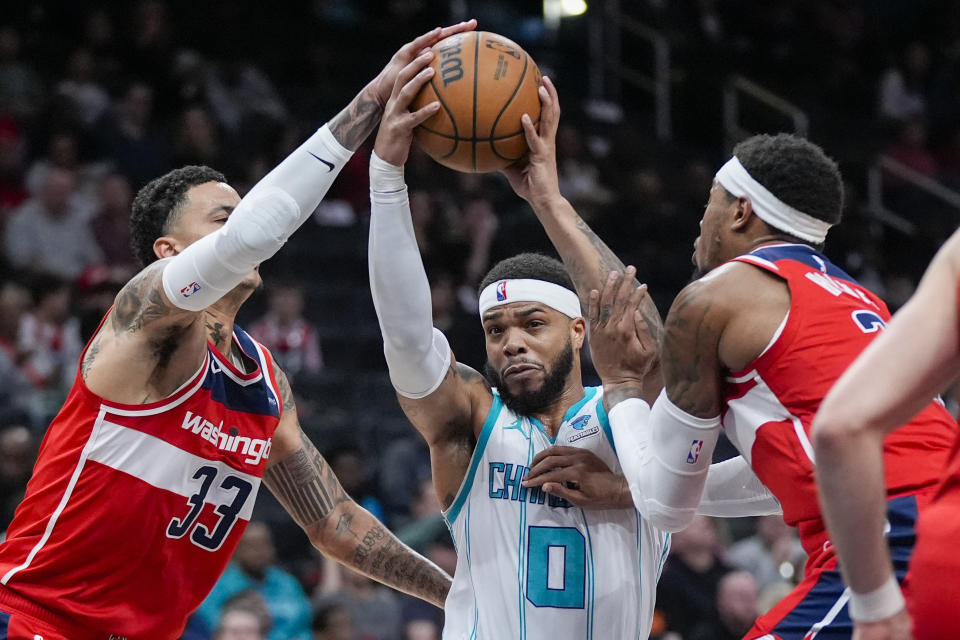 Washington Wizards forwards Kyle Kuzma (33) and Richaun Holmes (22) defend against Charlotte Hornets forward Miles Bridges (0) during the first half of an NBA basketball game Friday, March 8, 2024, in Washington. (AP Photo/Alex Brandon)