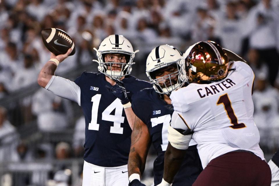 Penn State quarterback Sean Clifford (14) throws a pass to wide receiver Parker Washington, while Minnesota defensive lineman Trill Carter (1) is blocked during the first half of an NCAA college football game Saturday, Oct. 22, 2022, in State College, Pa. (AP Photo/Barry Reeger)