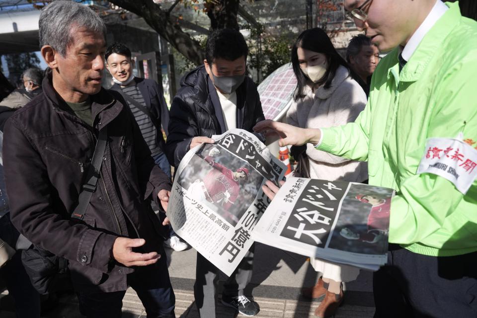 A staff distributes an extra edition of the Yomiuri Shimbun newspaper reporting on Shohei Ohtani to move to the Los Angeles Dodgers Sunday, Dec. 10, 2023, in Tokyo. (AP Photo/Eugene Hoshiko)