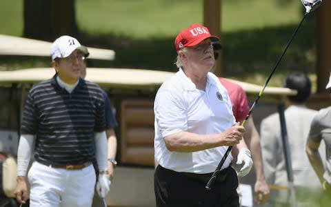 Donald Trump looks on after hitting a shot during a round of golf with Japan's Prime Minister Shinzo Abe play golf at Mobara Country Club in Chiba prefecture - Credit: Reuters