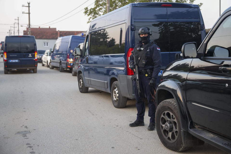 A police officers stand guard in the village of Dubona, some 50 kilometers (30 miles) south of Belgrade, Serbia, near the scene of a Thursday night attack that killed eight people and wounded 13, on Friday, May 5, 2023. Police looking for a 21-year-old suspect who fled after the attack. (AP Photo/Armin Durgut)