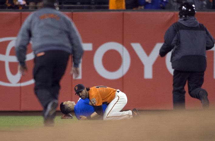 San Francisco Giants’ outfielder Angel Pagan holds down a man who ran onto the field during Friday's game against the Dodgers. (AP)