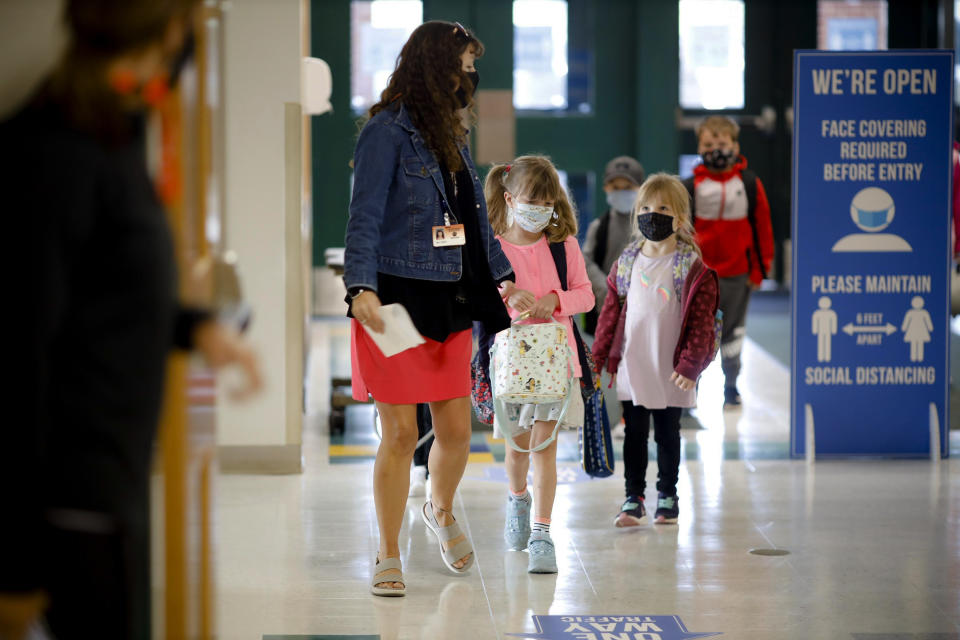 Kindergarten students are led into the building on the first day of in-person classes at Lee Elementary School on Wednesday, Sept. 16, 2020 in Lee, Mass. (Stephanie Zollshan/The Berkshire Eagle via AP)