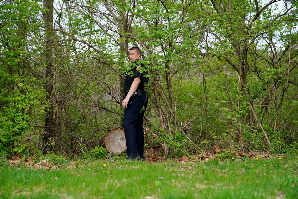 A Cincinnati Police officer searches a wooded area for monkeys reported to be on the loose, Thursday, April 8, 2021, at St. Joseph's Cemetery in the East Price Hill neighborhood of Cincinnati.