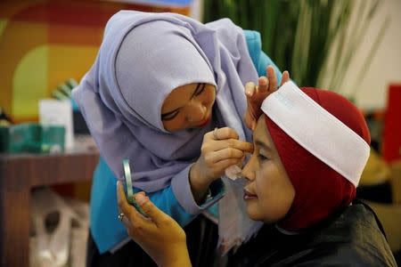 A saleswoman from Wardah cosmetics, an Indonesian brand specialising in products for Muslim women, attends to a customer at a sales booth in a mall in Jakarta, Indonesia, August 3, 2016. Picture taken August 3, 2016. REUTERS/Beawiharta