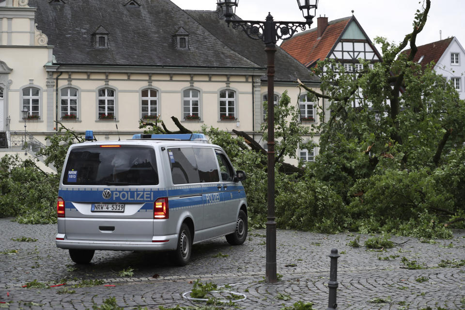 A police vehicle stands next to a downed tree from severe weather in Lippstadt, Germany, Friday, May 20, 2022. Meteorologists had warned that heavy rainfall and hail were expected in western and central Germany on Friday, with storms producing wind gusts up to 130 kph (81 mph). (Friso Gentsch/dpa via AP)