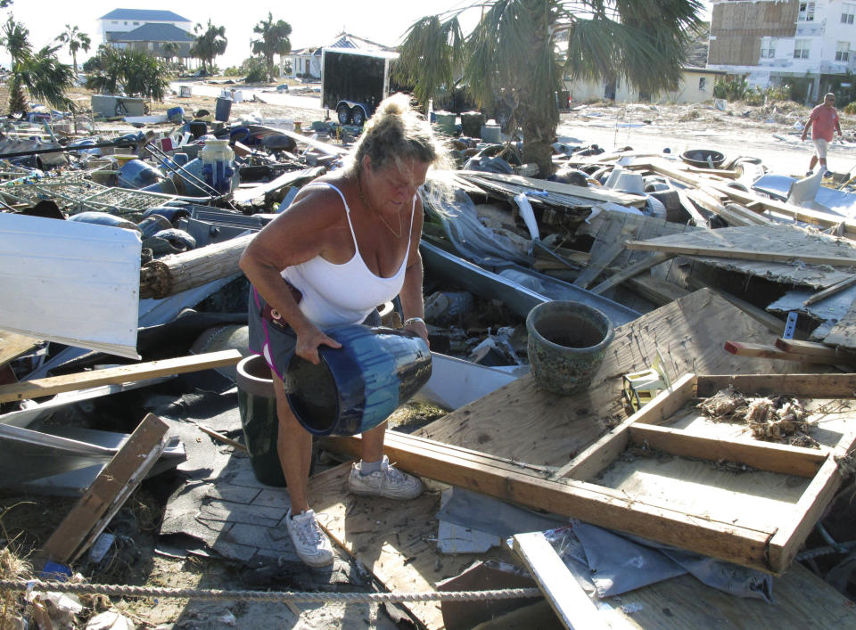 En esta fotografía del 14 de octubre de 2018, Dena Frost mueve una vasija de los escombros de su negocio en la localidad de Mexico Beach, Florida. (AP Foto/Russ Bynum)