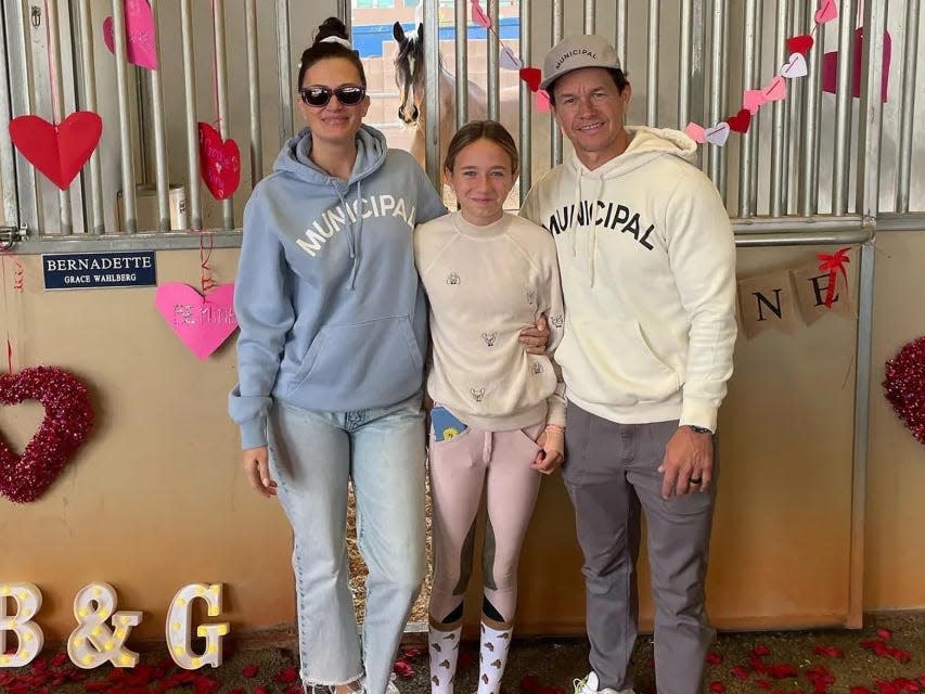 Rhea Durham (left), Grace Wahlberg (center), and Mark Wahlberg (right) in front of horse stall.