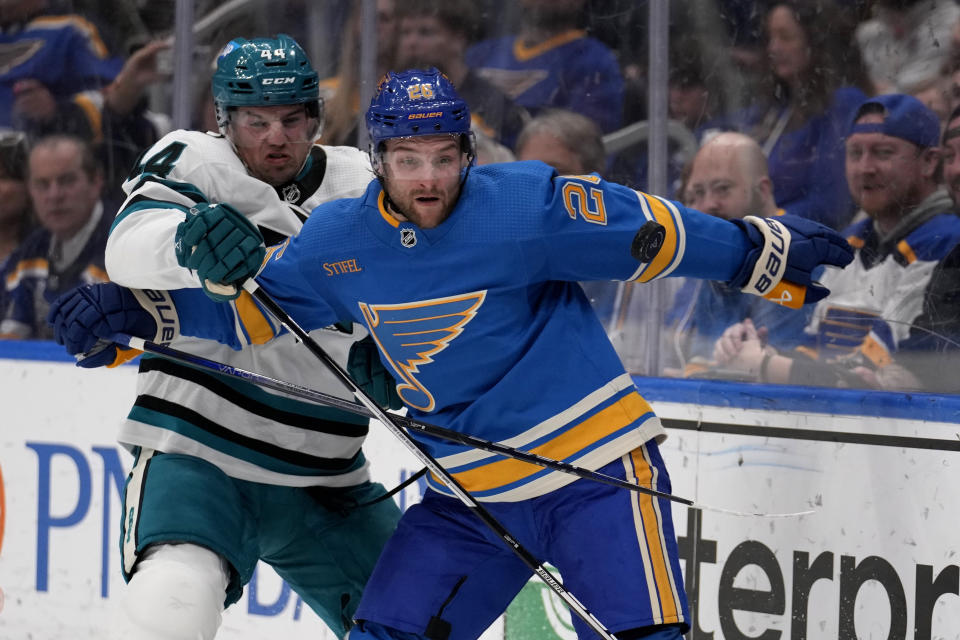 St. Louis Blues' Nathan Walker, right, and San Jose Sharks' Marc-Edouard Vlasic (44) chase after a loose puck during the second period of an NHL hockey game Saturday, March 30, 2024, in St. Louis. (AP Photo/Jeff Roberson)
