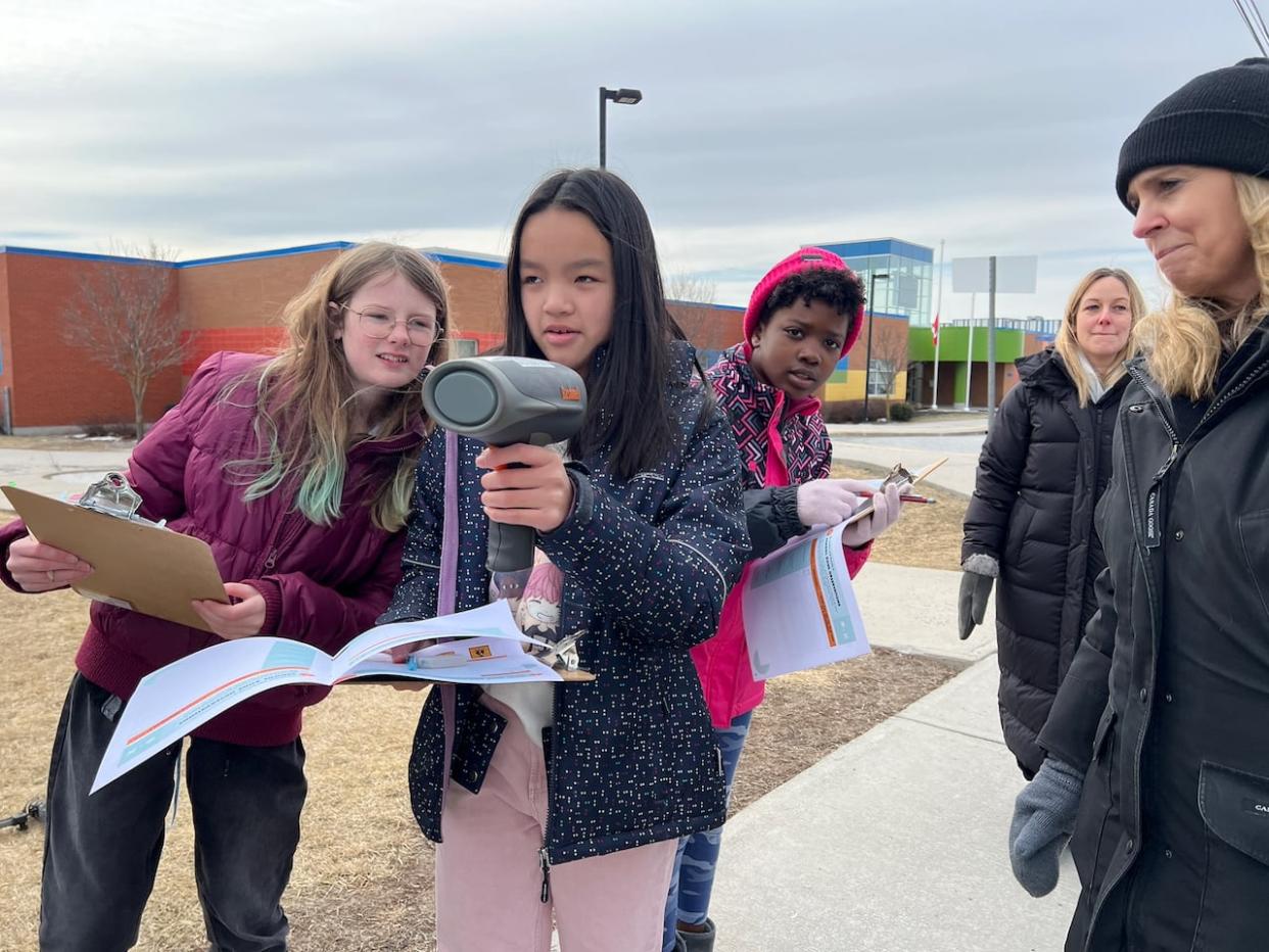 From left, St. Cecilia students Orlagh Ryan, Trisie Nguyen and Ada Ndekwu measure and record the speeds of drivers on Cambrian Road in front of their school. (Giacomo Panico/CBC - image credit)