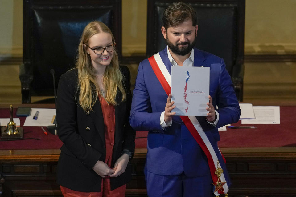 Chilean President Gabriel Boric holds the final draft of the new national Constitution, presented to him by Constitutional Council President Breatriz Hevia as they stand before the council at the former National Congress building in Santiago, Chile, Tuesday, Nov. 7, 2023. Voters will decide on Dec. 17 to accept or reject the new Constitution. (AP Photo/Esteban Felix)