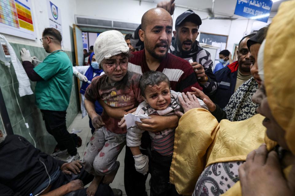 A man carries children injured in Israeli bombardment, at the al-Najjar hospital in Rafah in the southern Gaza Strip on March 24, 2024, amid the ongoing conflict between Israel and the militant group Hamas.