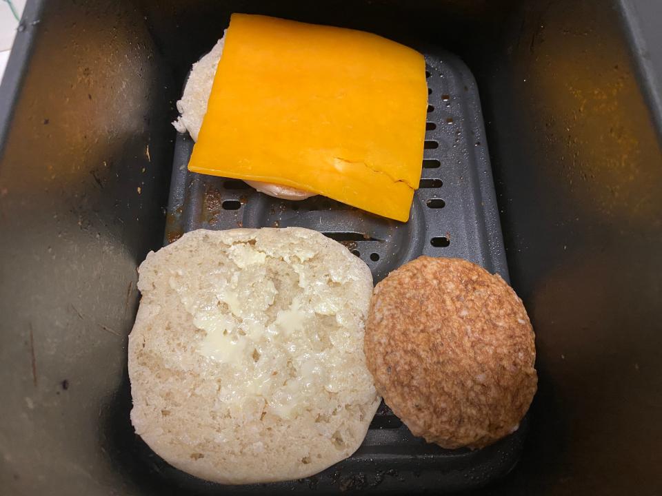 An english muffin with cheese on it and a sausage patty in an air fryer