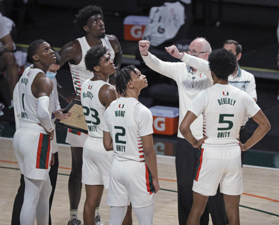 Miami coach Jim Larranaga talks with players as they look up toward the board showing the Hurricanes trailing Purdue during the first half of an NCAA college basketball game Tuesday, Dec. 8, 2020, in Coral Gables, Fla. (Al Diaz/Miami Herald via AP)