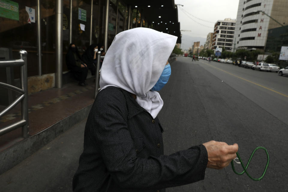 A woman holds prayer beads as she crosses an intersection in downtown Tehran, Iran, Tuesday, May 11, 2021. (AP Photo/Vahid Salemi)