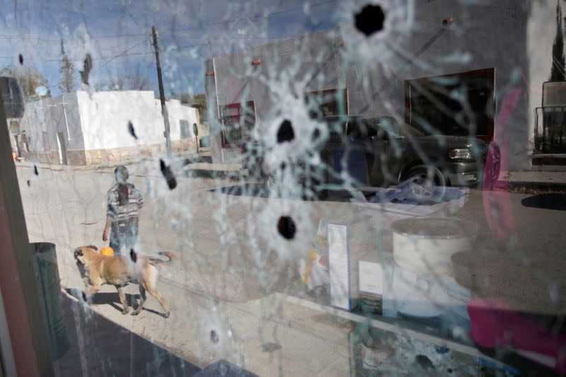 FILE PHOTO: A woman is pictured through a bullet-riddled glass of a store, days after a gun battle between police and hitmen, in the municipality of Villa Union