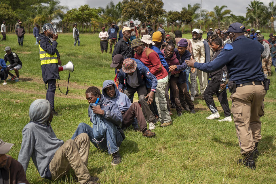 Homeless recyclers and other destitute people, some of whom said they have not eaten in three days, are asked to practice social distancing by police as they lineup in a Johannesburg park, waiting to receive food baskets from private donors, Thursday, April 9, 2020. Because of South Africa's imposed lockdown to contain the spread of COVID-19, many people who don't have savings and are unable to work are not able to buy food. (AP Photo/Jerome Delay)