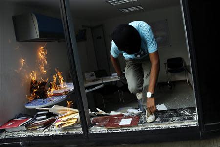 An anti-government protester jumps through a window after setting fire to an office as they loot a public building in Caracas March 12, 2014. REUTERS/Carlos Garcia Rawlins