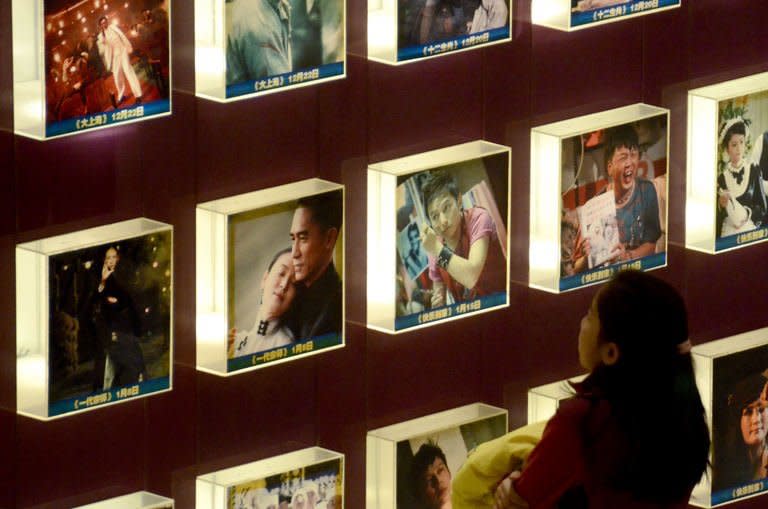 A woman looks at a set of illuminated movie posters at a cinema in Beijing on January 18,2013. Ten new movie screens open each day in China as the popularity of cinema soars in the country, but the appeal of Chinese films has failed to maintain the pace