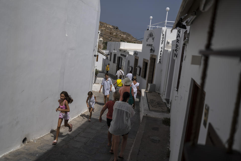 FILE - Tourists walk in Lindos, on the Aegean Sea island of Rhodes, southeastern Greece, on Thursday, July 27, 2023. Greece’s resort island of Rhodes is nursing its wounds after 11 days of devastating wildfires. (AP Photo/Petros Giannakouris, File)