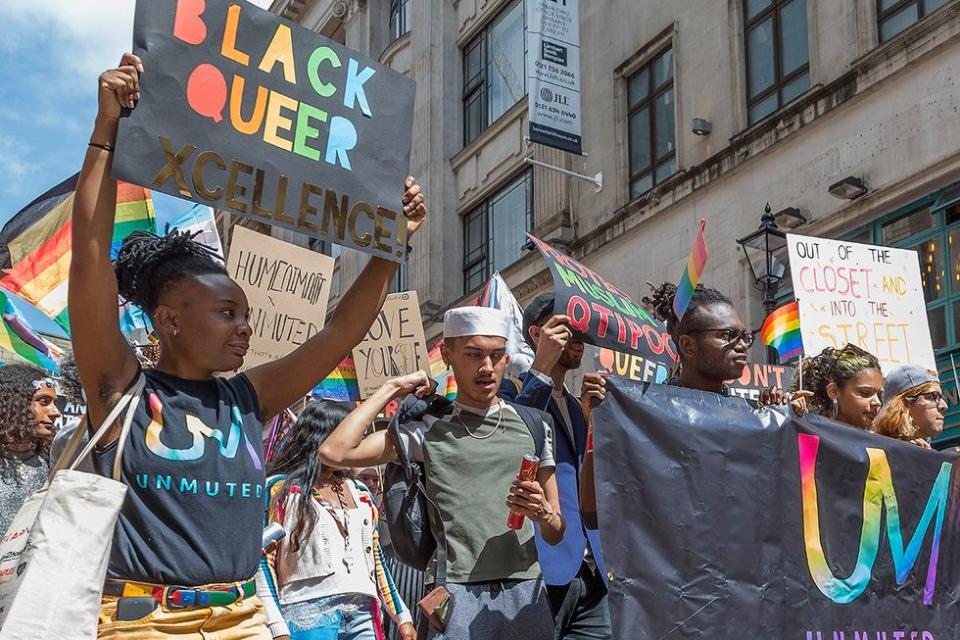 Birmingham, UK - May 25, 2019 - People of Colour carry flags and banners in support of the LGBTQI community in the Pride procession through the city centre.