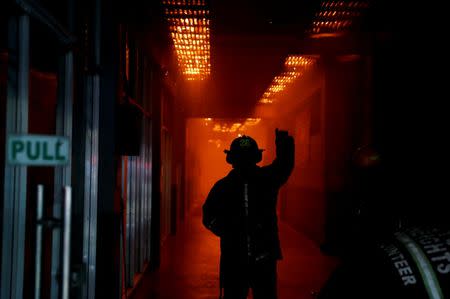 A fireman gives a hand signal to fellow firefighters as a shopping centre burns at the University of the Philippines campus in Quezon City, Metro Manila, Philippines, March 8, 2018. REUTERS/Erik De Castro