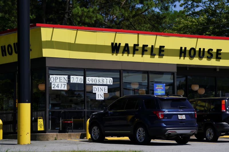 A sign in the window of a Waffle House announces that the restaurant is open to dine in service, in Smyrna