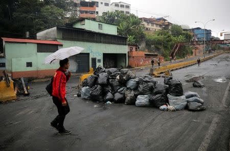 Un hombre camina al lado de la barricada luego de días de protestas contra el presidente venezolano Nicolás Maduro en la ciudad de Los Teques, cerca de Caracas, Venezuela, 19 de mayo de 2017. REUTERS/Carlos Barria