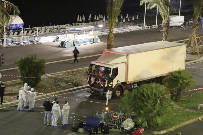 FILE - Authorities investigate a truck after it plowed through Bastille Day revelers in the French resort city of Nice, France, Thursday, July 14, 2016. Eight people go on trial Monday Sept.5, 2022 in a special French terrorism court for alleged roles in helping the attacker who drove a truck into the Nice beachfront on Bastille Day 2016, killing 86 people. (Sasha Goldsmith via AP, File)