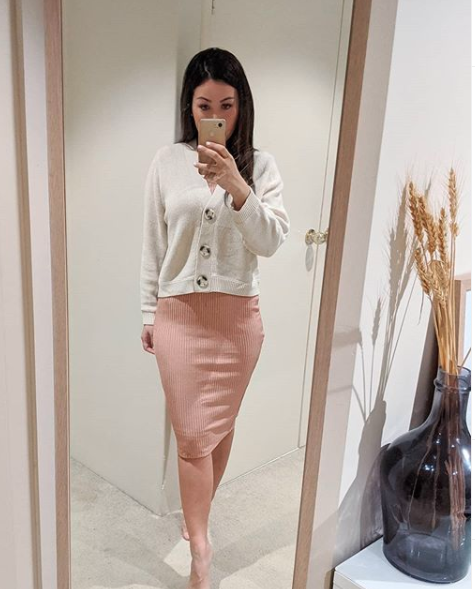 Woman wearing a pink skirt and a cream cardigan