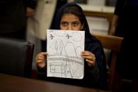 RNPS - PICTURES OF THE YEAR 2013 - Nabila Rehman, 9, holds up a picture she drew depicting the U.S. drone strike on her Pakistan village which killed her grandmother Mammana Bibi, at a news conference on Capitol Hill in Washington October 29, 2013. Nabila and her father and brother attended the news conference to highlight the personal costs in collateral damage for civilians killed and injured in the U.S. drone strike program. REUTERS/Jason Reed (UNITED STATES - Tags: POLITICS MILITARY TPX)