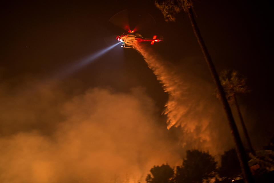 <p>A helicopter drops water over the Lilac Fire on December 8 near Bonsall, California.</p>
